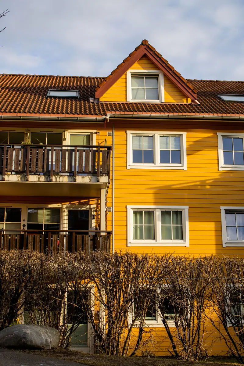 Gult trehus med balkong under en lys himmel