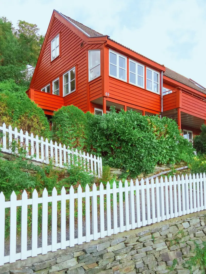Rødt trehus med hvitt stakittgjerde i Bergen
